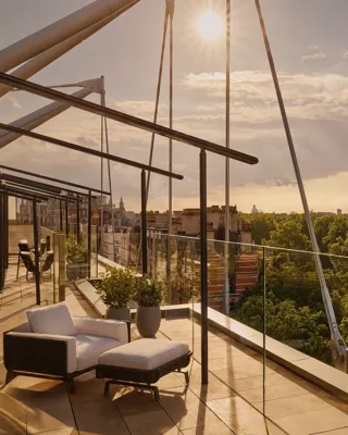 Rooftop terrace at sunset with lounge chairs and Hyde Park views.
