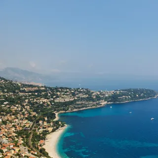 Aerial view of the French Riviera coastline with turquoise bays, hillside villas and boats on the Mediterranean Sea.