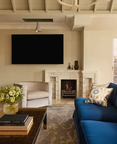 Contemporary living space with blue sofa, marble fireplace, armchair, and wall-mounted TV.