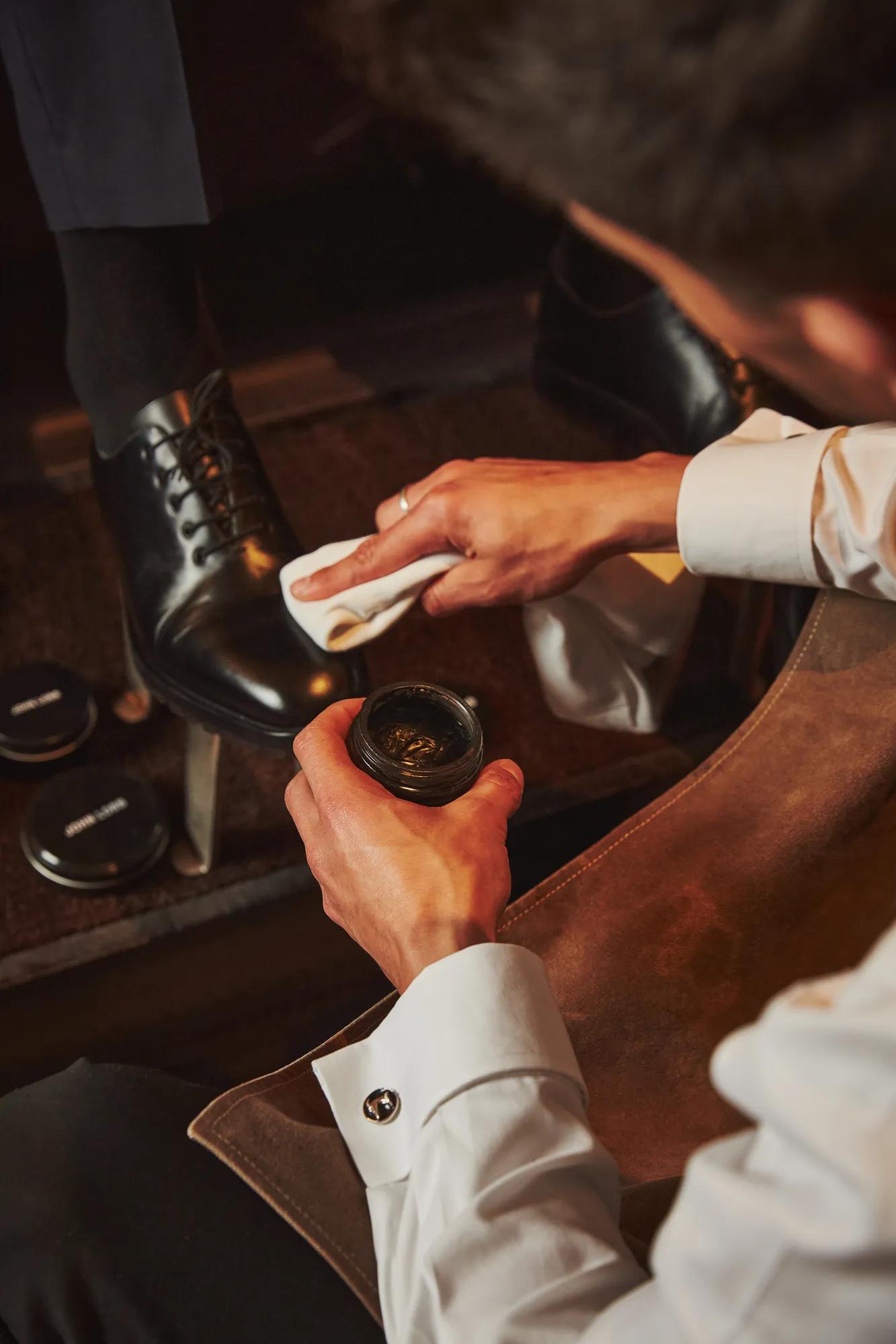 Attendant polishes a guest’s black dress shoe, applying cream and buffing the leather to a shine.
