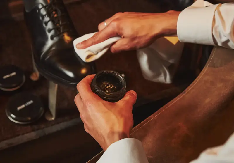 Attendant polishes a guest’s black dress shoe, applying cream and buffing the leather to a shine.