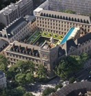 Aerial view of a historic city block with central courtyard garden, rooftop pool and surrounding stone buildings