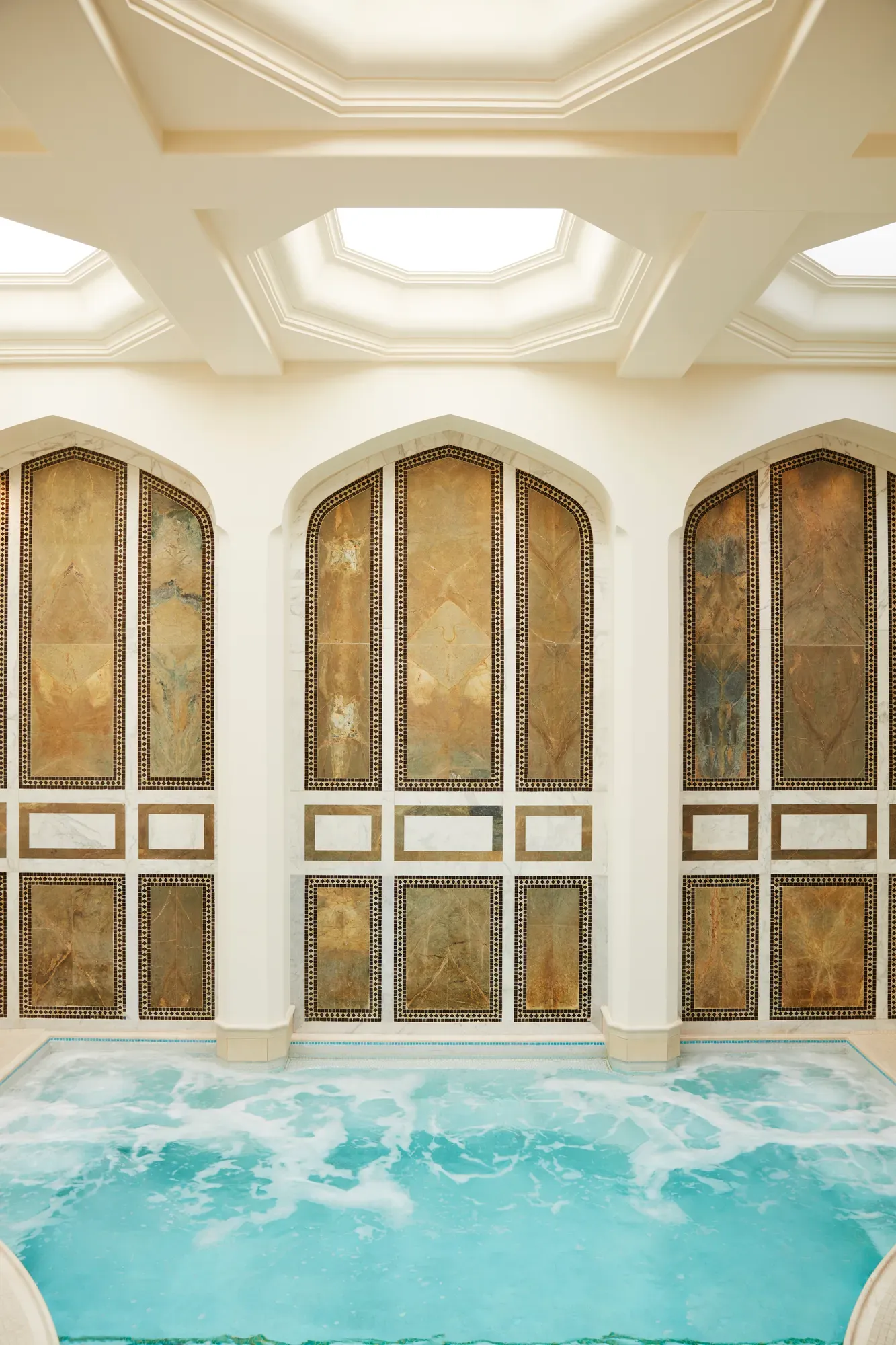 Indoor mineral pool at The Spa at The Maybourne Beverly Hills with arched marble walls and natural skylight ceiling.