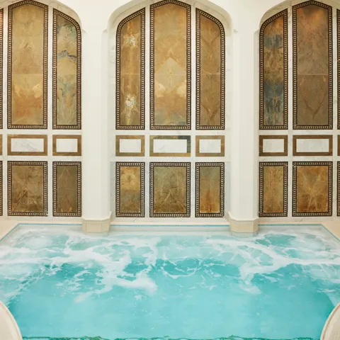 Indoor mineral pool at The Spa at The Maybourne Beverly Hills with arched marble walls and natural skylight ceiling.