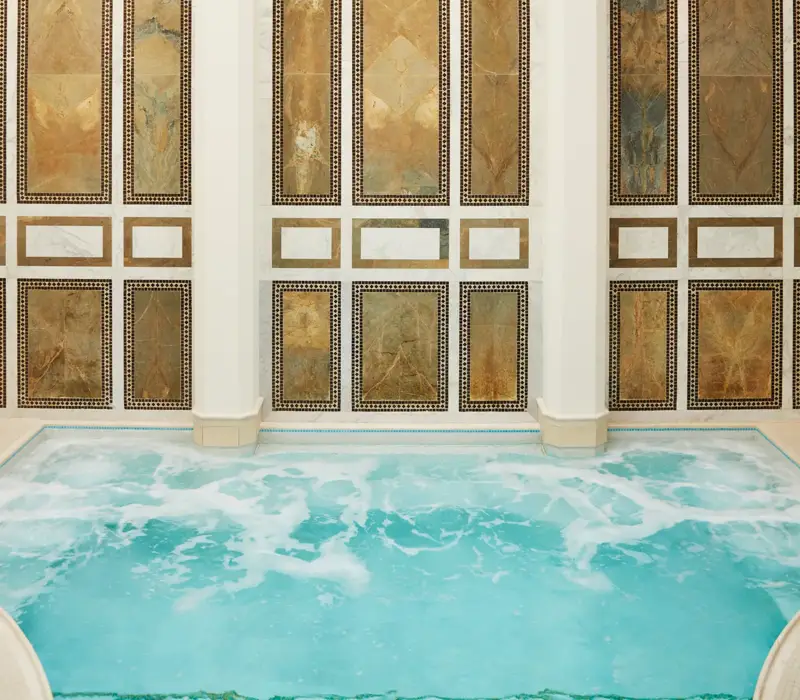 Indoor mineral pool at The Spa at The Maybourne Beverly Hills with arched marble walls and natural skylight ceiling.