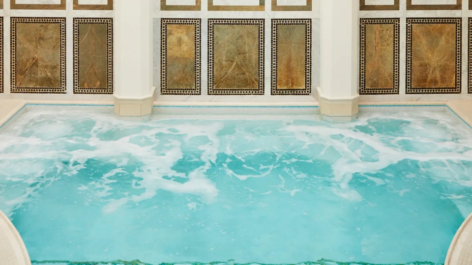 Indoor mineral pool at The Spa at The Maybourne Beverly Hills with arched marble walls and natural skylight ceiling.