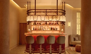 Warm, intimate bar with a glowing marble counter, curved bar stools, and a decorative overhead light feature.