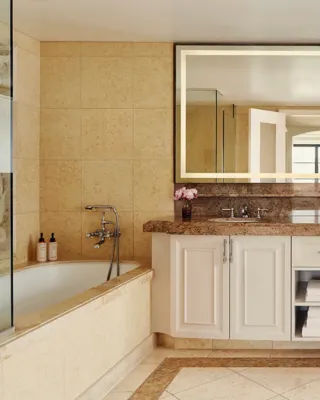 Spacious bathroom with granite double vanity, large backlit mirror, and a soaking tub with handheld shower.