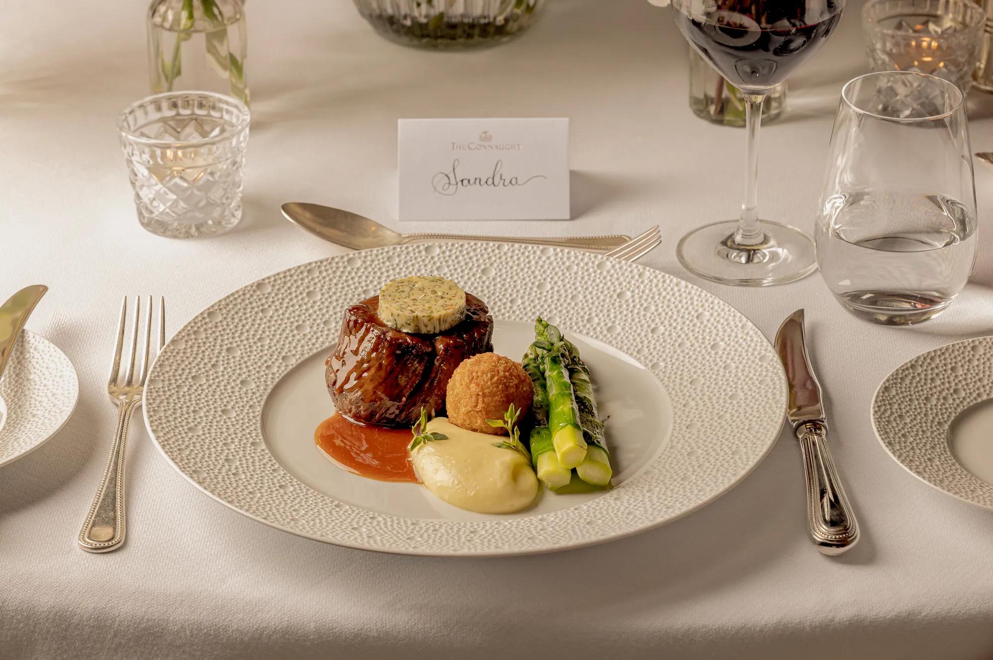 Gourmet beef dish with asparagus and potato purée served on an elegantly set dining table.
