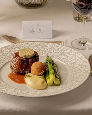 Gourmet beef dish with asparagus and potato purée served on an elegantly set dining table.