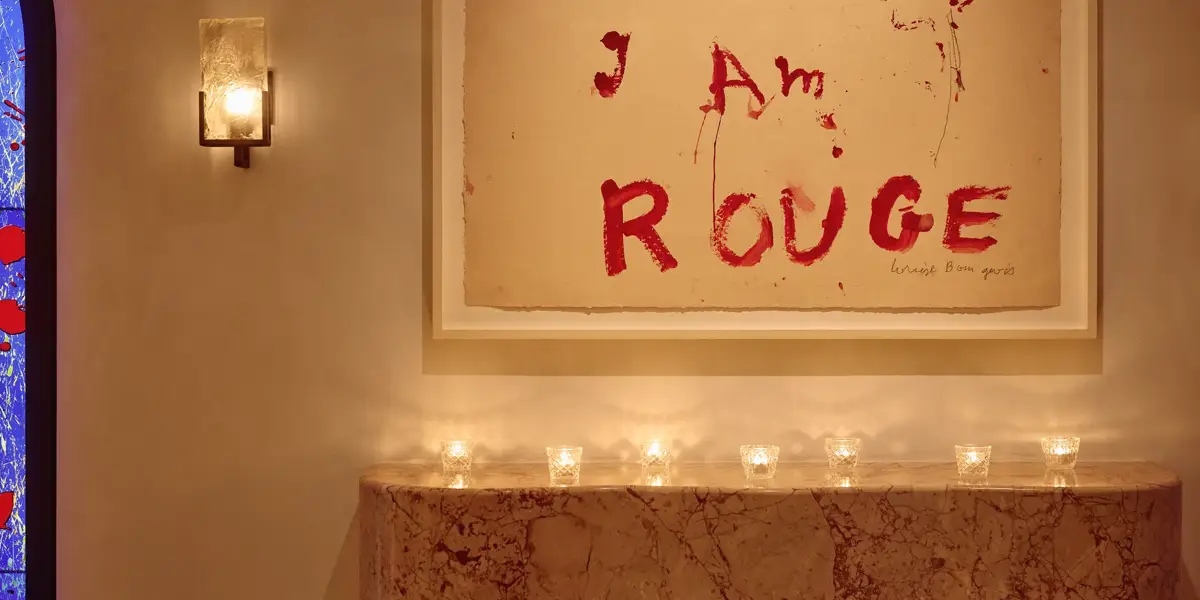 Marble mantel with small candles beneath artwork reading “I Am Rouge” in bold red text.