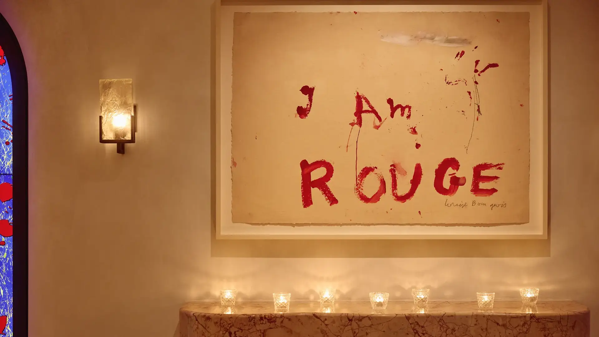 Marble mantel with small candles beneath artwork reading “I Am Rouge” in bold red text.