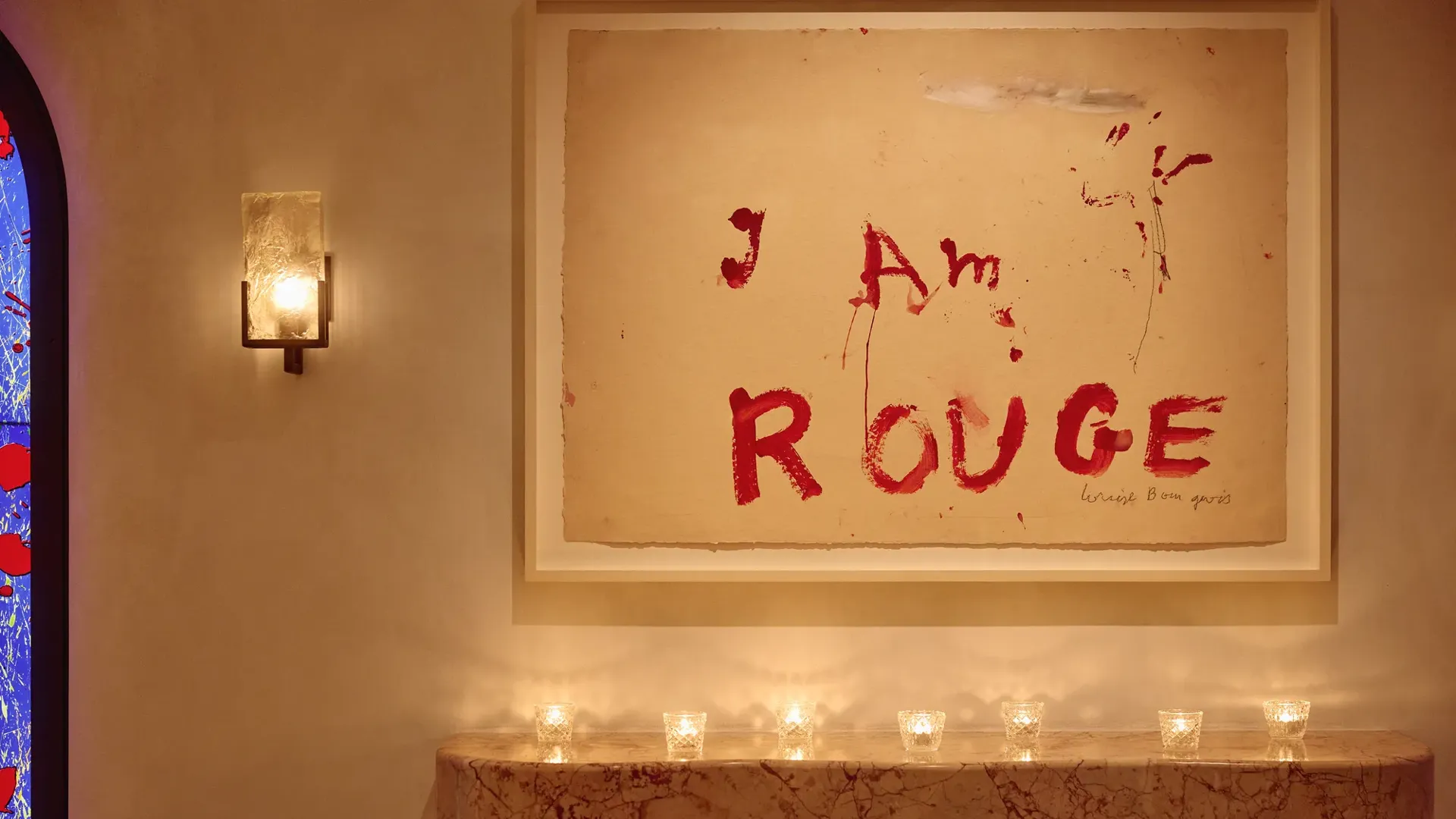 Marble mantel with small candles beneath artwork reading “I Am Rouge” in bold red text.