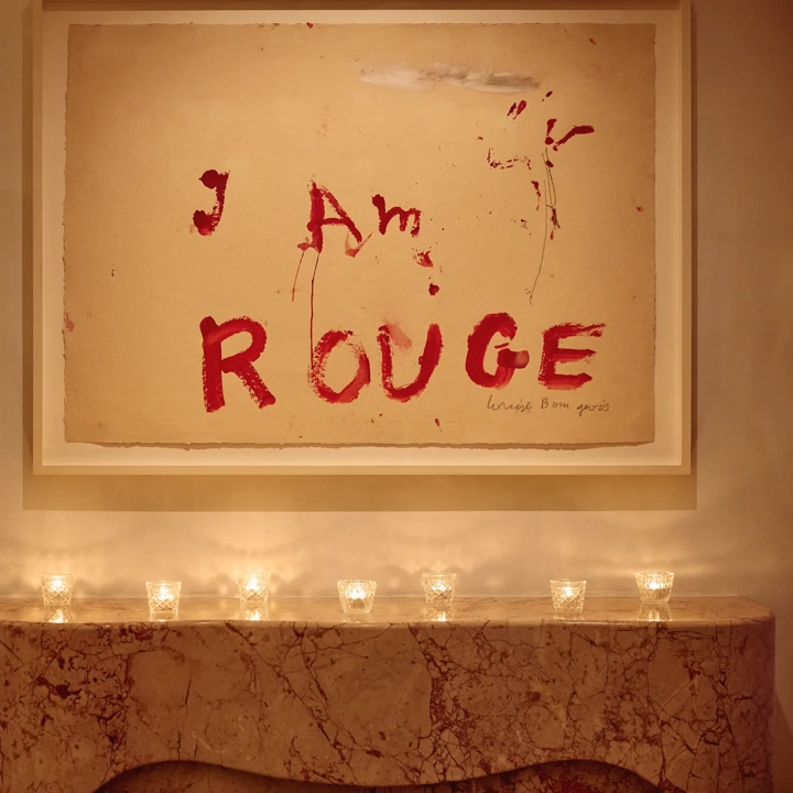 Marble mantel with small candles beneath artwork reading “I Am Rouge” in bold red text.