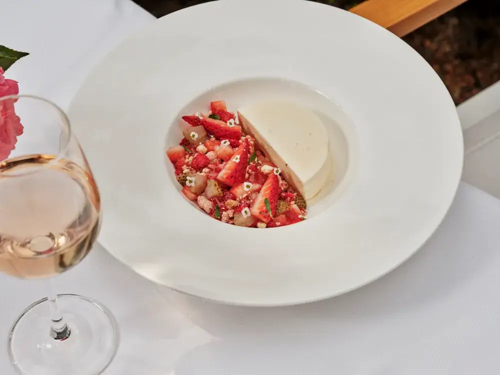 Dessert plate with panna cotta and fresh strawberries, served with a glass of rosé wine.
