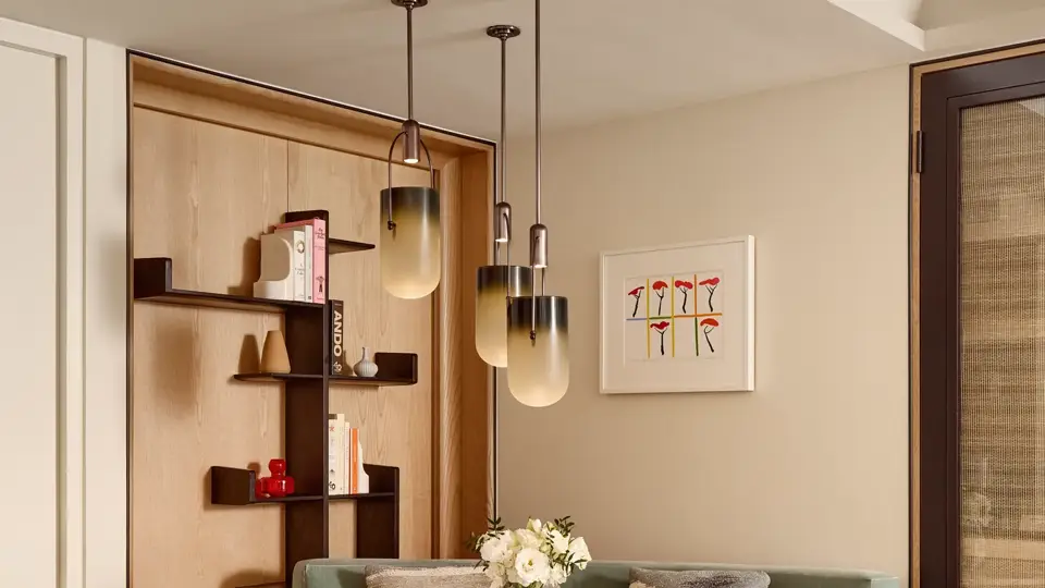Intimate dining area with a marble-topped round table, black chairs, green banquette seating, and three amber glass pendant lights.