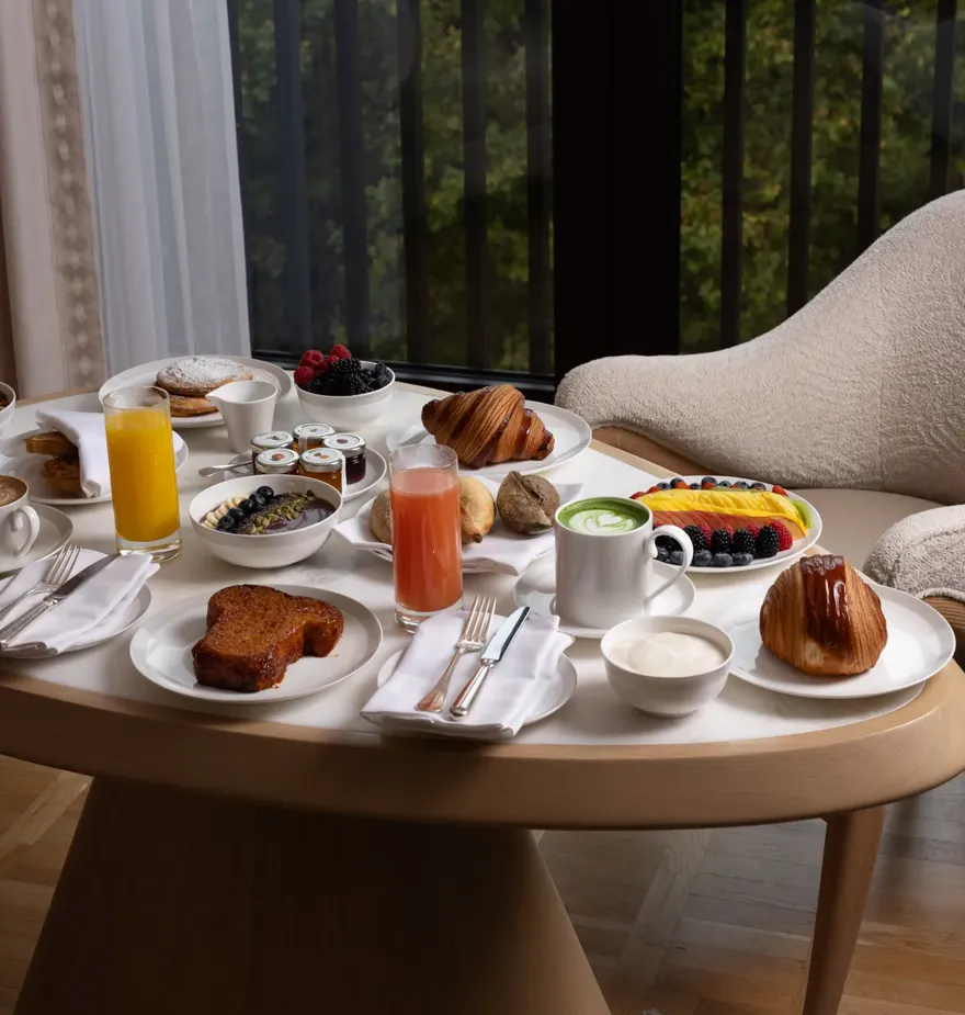 A neatly arranged breakfast table featuring plates of food, fresh fruit, and warm drinks, set in soft morning light to create a welcoming start to the day.