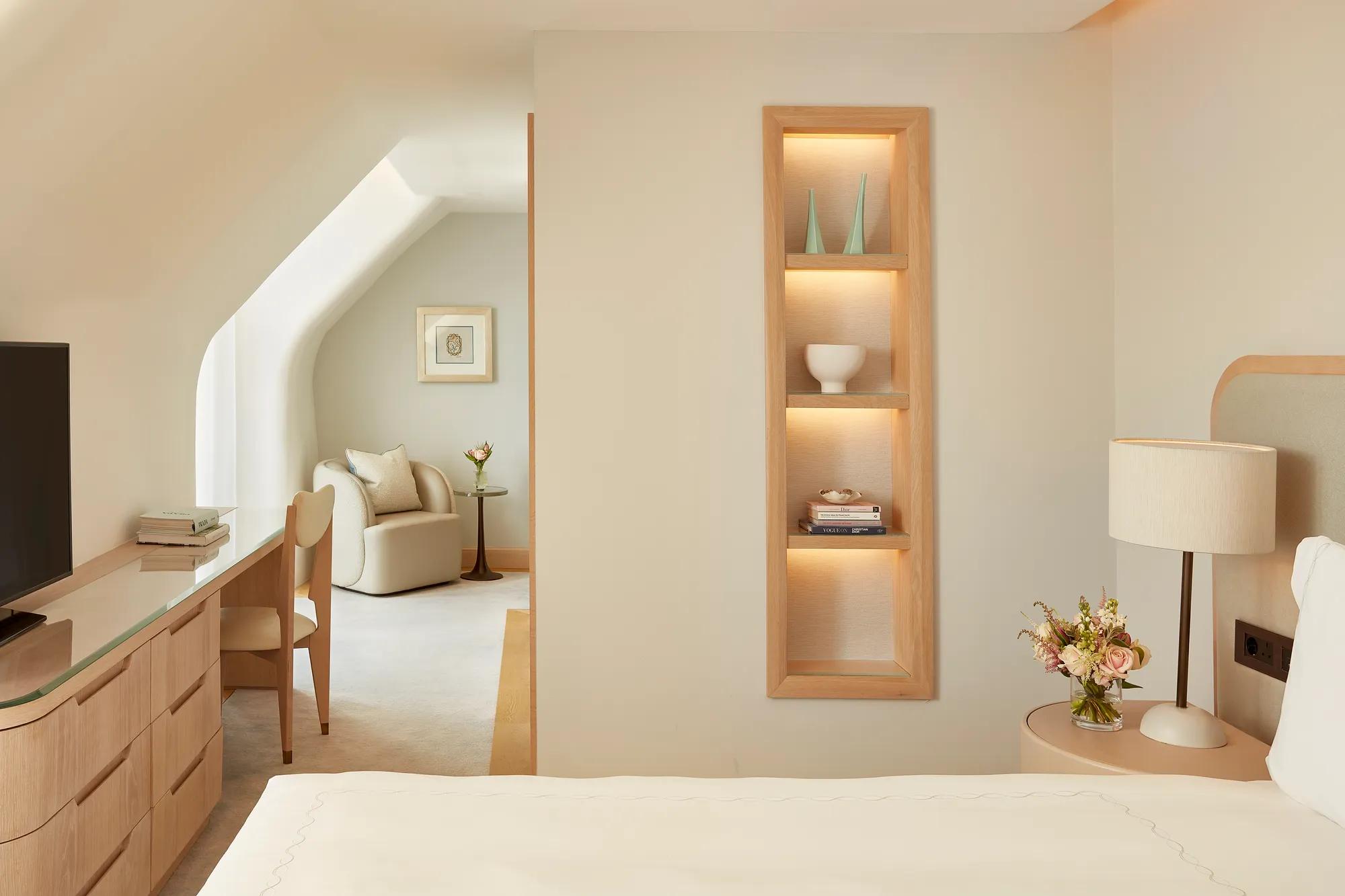 Elegant bedroom with built-in shelving, desk area, and adjoining lounge space.