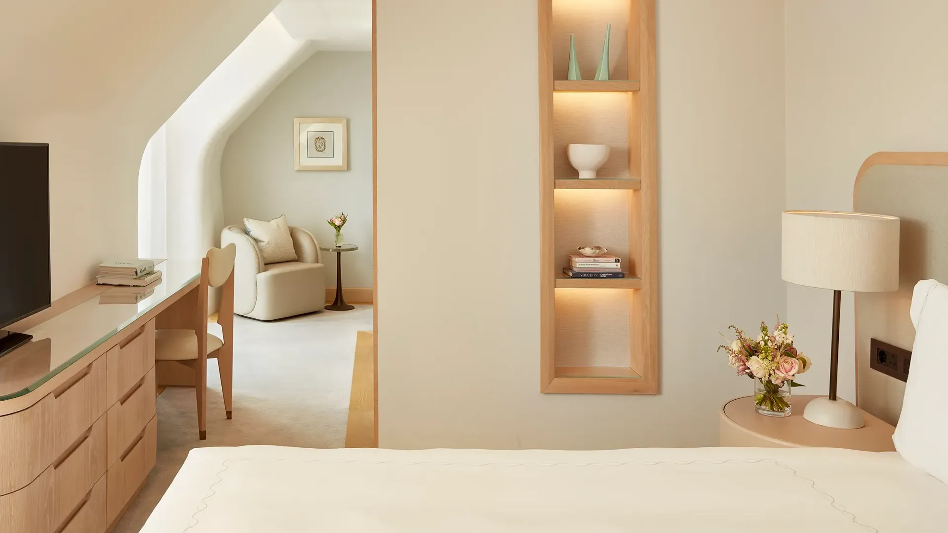 Elegant bedroom with built-in shelving, desk area, and adjoining lounge space.