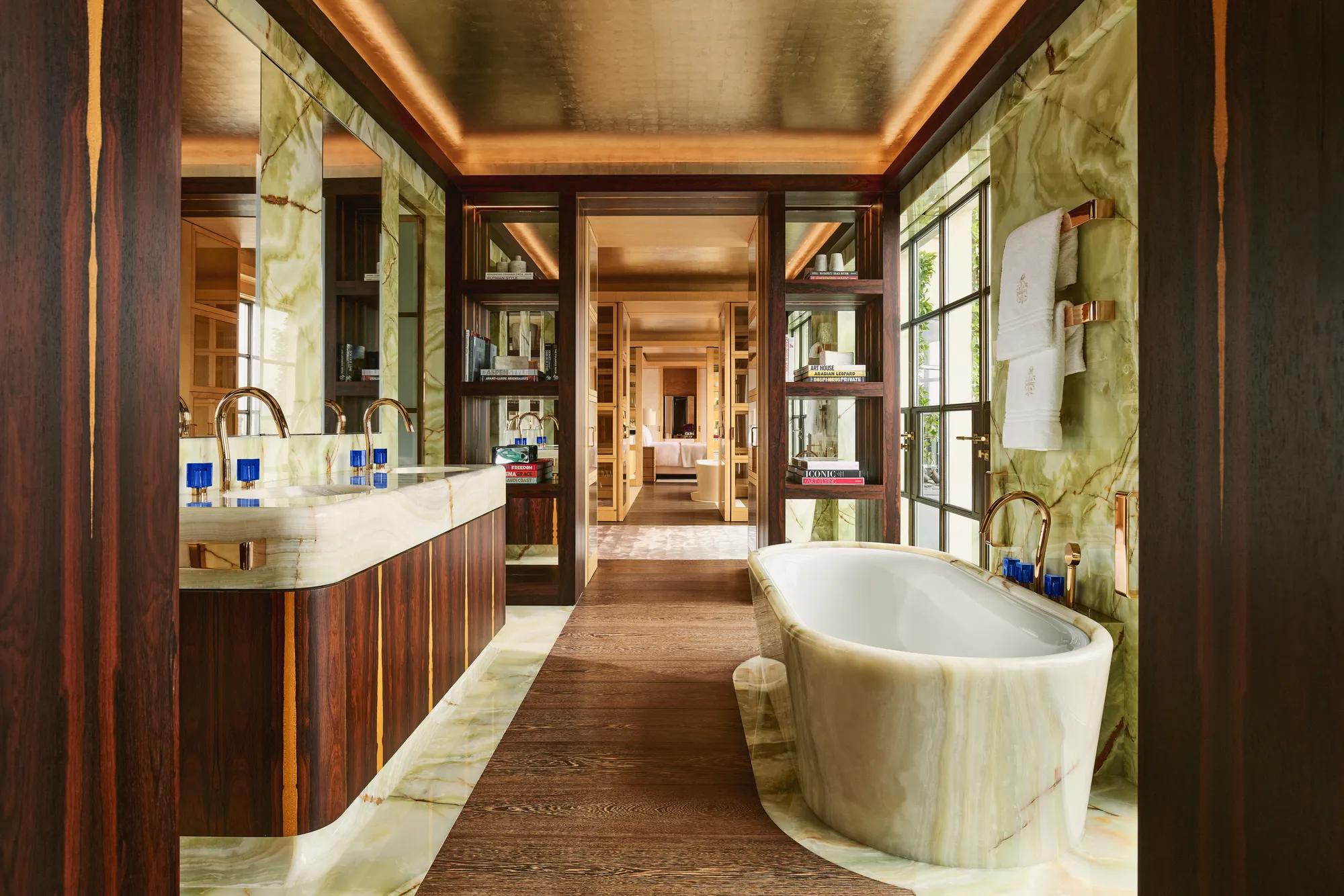 Luxurious bathroom at Claridge’s with a marble freestanding bathtub, double vanity, and warm wood and onyx finishes.