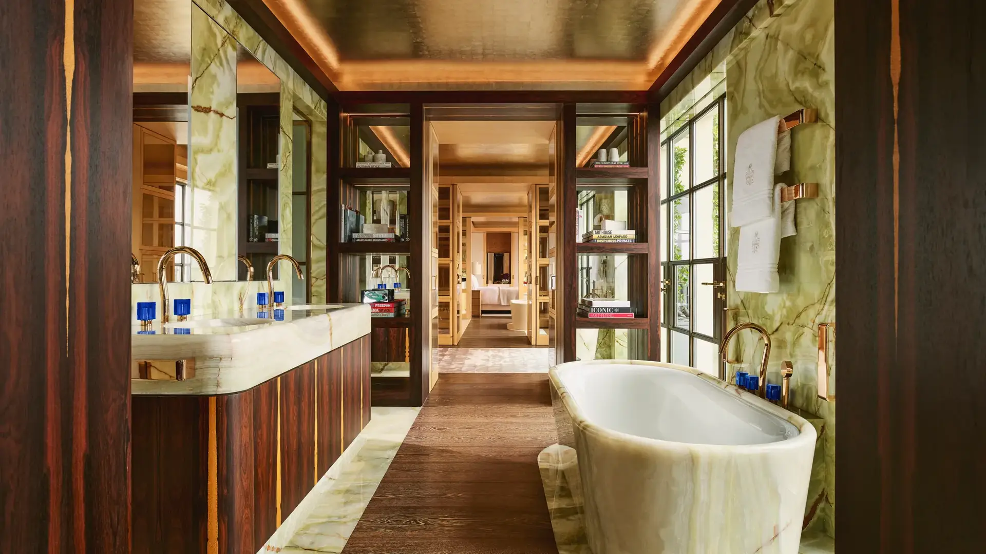 Luxurious bathroom at Claridge’s with a marble freestanding bathtub, double vanity, and warm wood and onyx finishes.