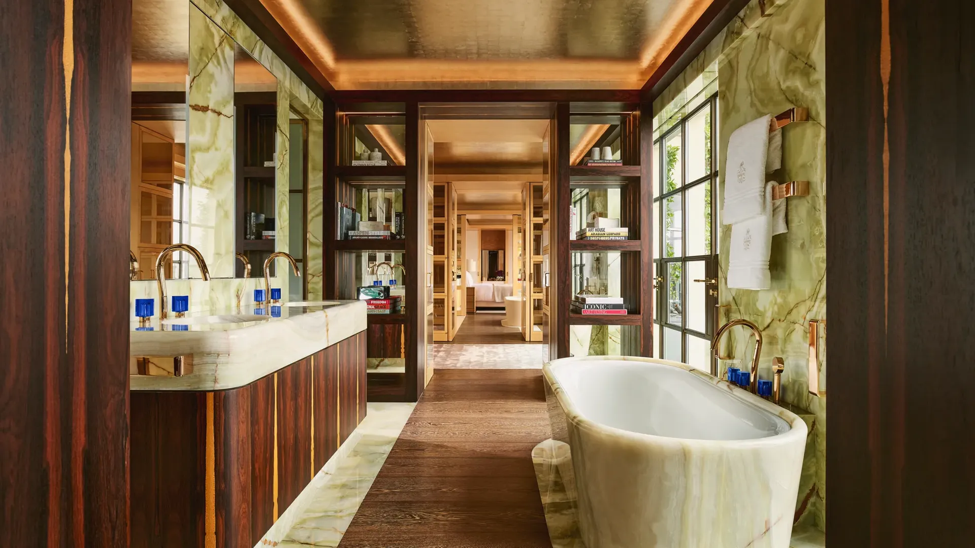 Luxurious bathroom at Claridge’s with a marble freestanding bathtub, double vanity, and warm wood and onyx finishes.