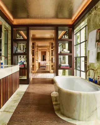 Luxurious bathroom at Claridge’s with a marble freestanding bathtub, double vanity, and warm wood and onyx finishes.