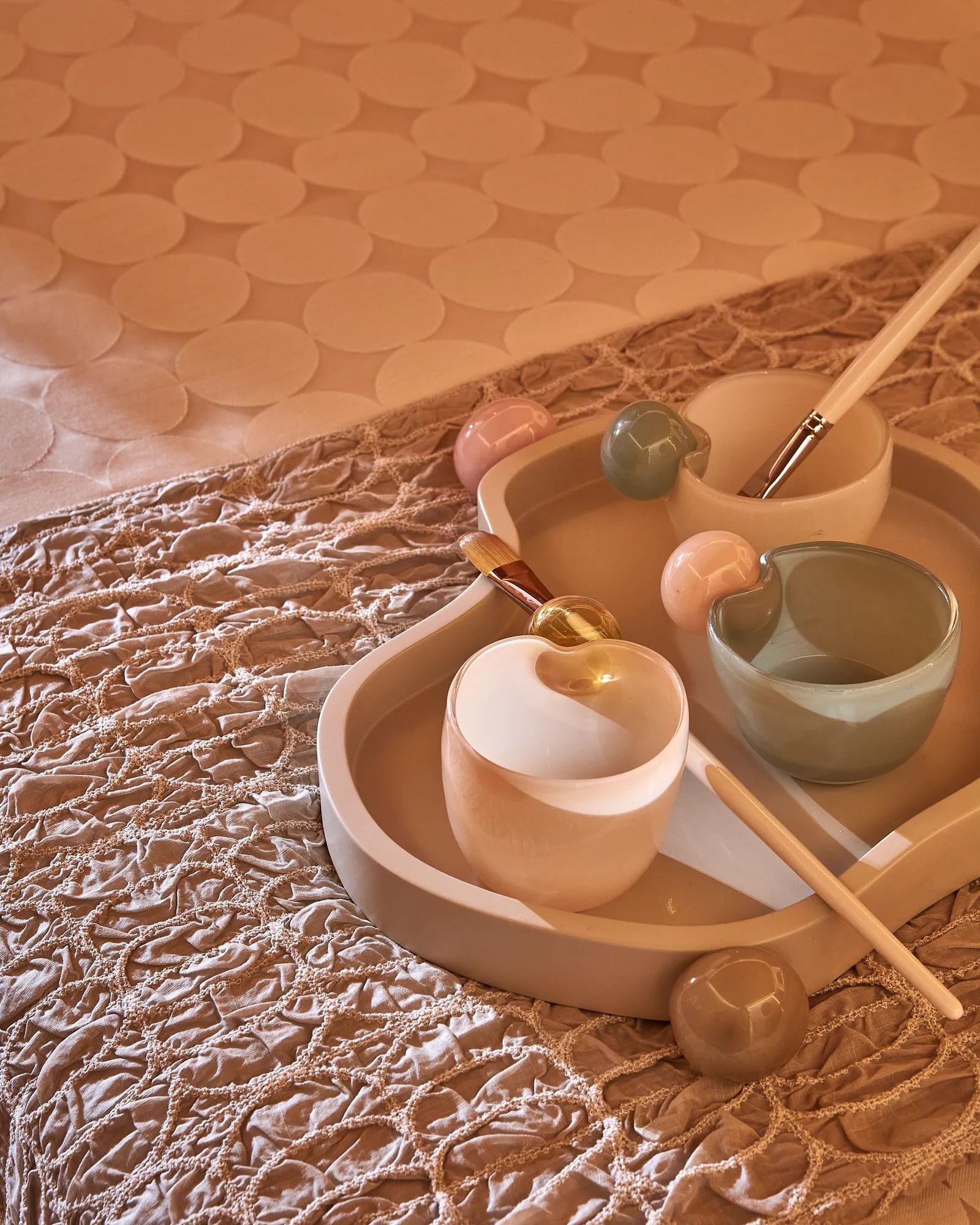 Tray with ceramic bowls, brushes and tools arranged for a spa or wellness treatment.