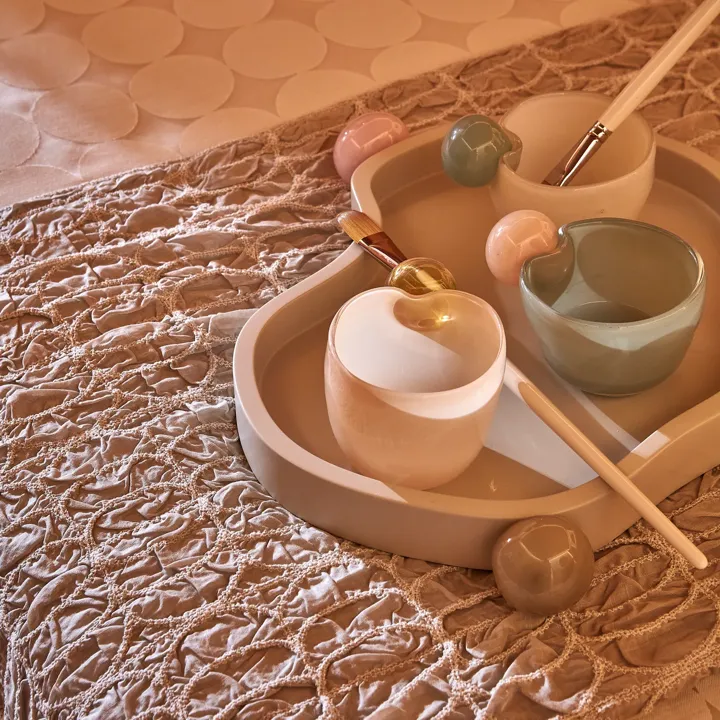 Tray with ceramic bowls, brushes and tools arranged for a spa or wellness treatment.