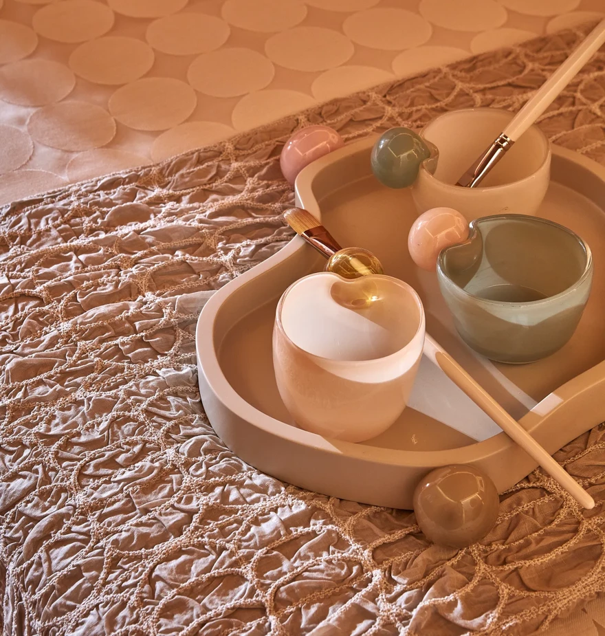 Tray with ceramic bowls, brushes and tools arranged for a spa or wellness treatment.