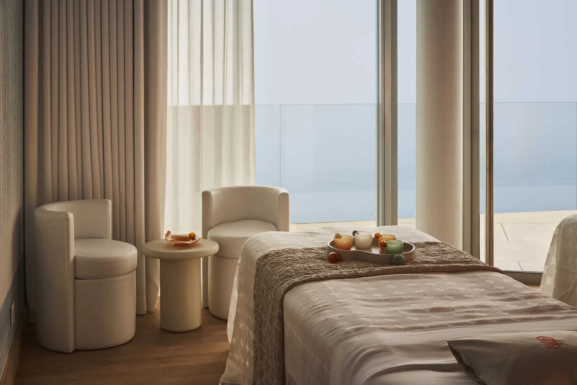 Treatment room with a padded therapy bed, soft lighting, and minimal décor.