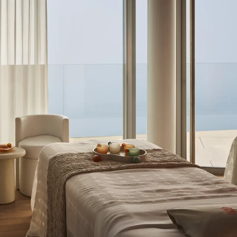 Treatment room with a padded therapy bed, soft lighting, and minimal décor.