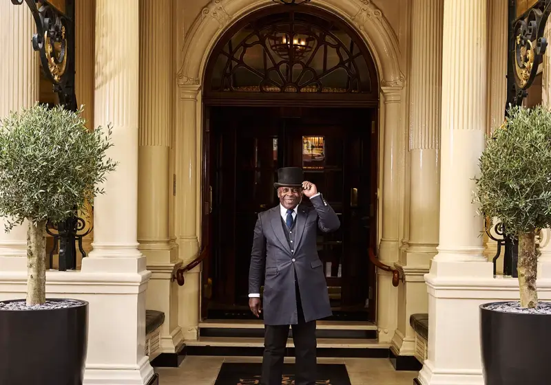 Doorman standing at The Connaught Hotel entrance beneath ornate black canopy.