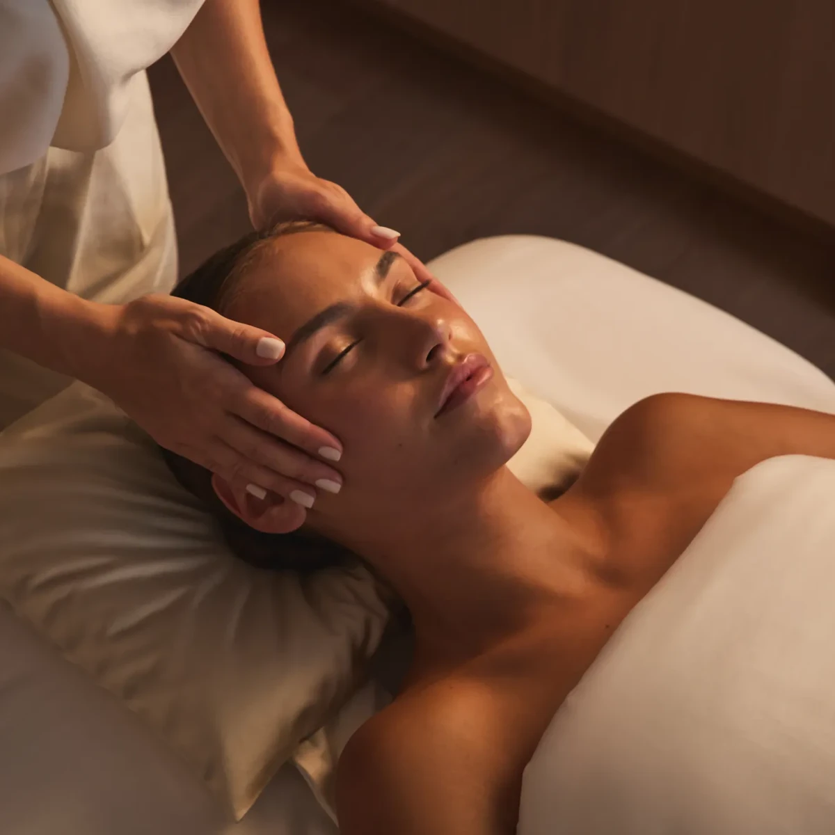 Therapist gently massaging a guest’s temples during a relaxing facial treatment.