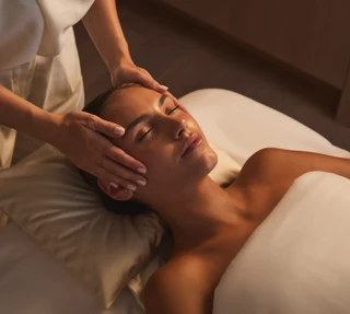 Therapist gently massaging a guest’s temples during a relaxing facial treatment.