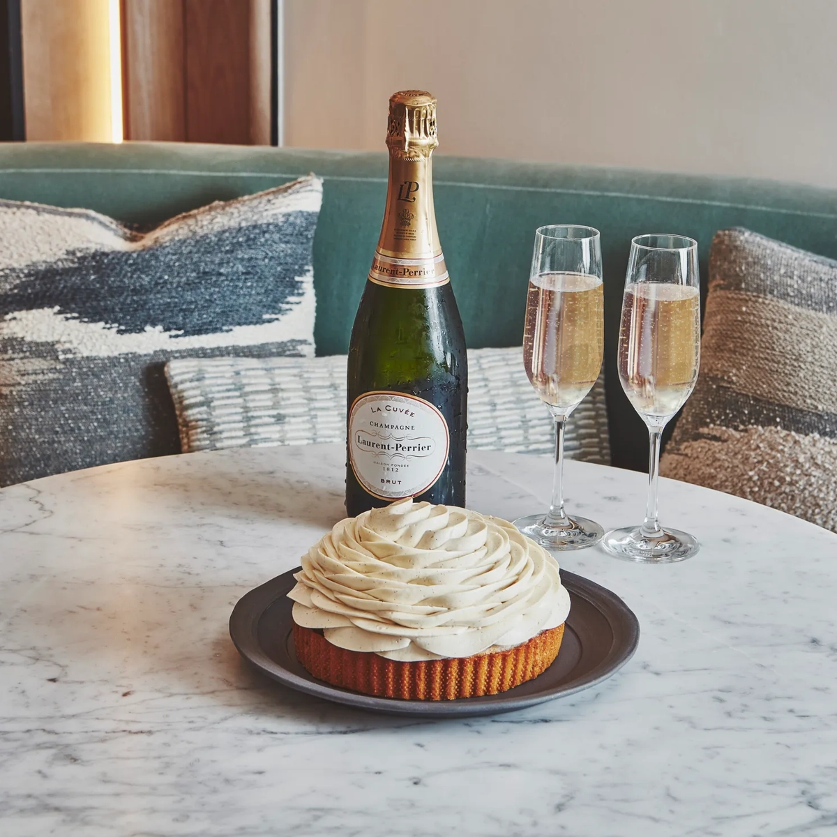 A polished marble table holding two filled champagne glasses, with soft light reflecting off the stone surface and bubbles rising gently in each glass