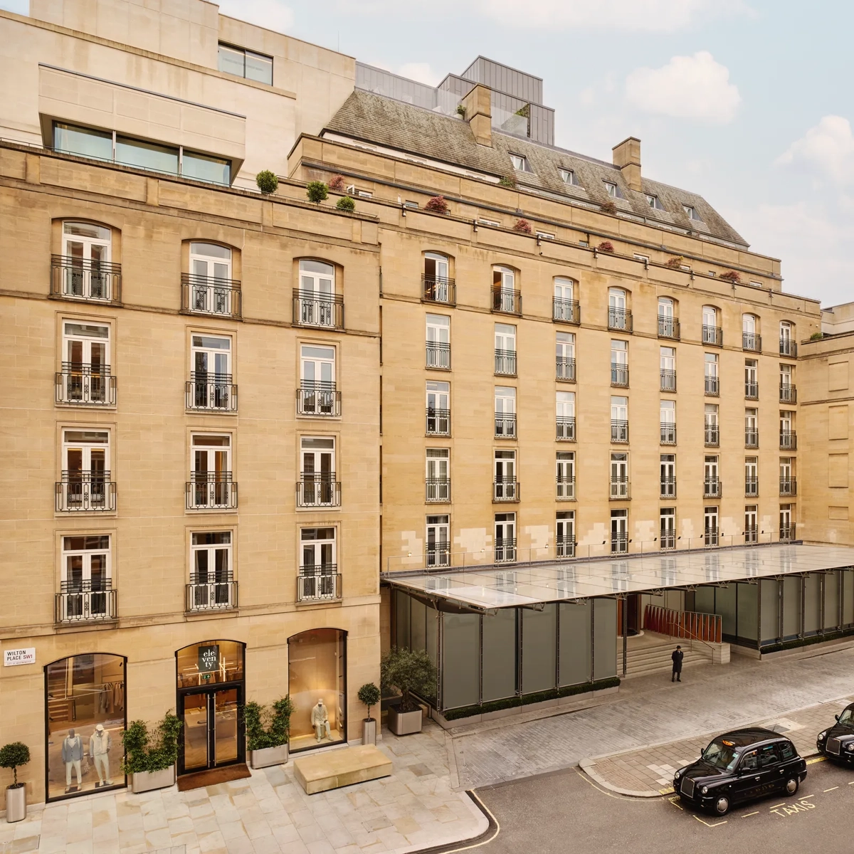 Exterior view of The Emory hotel with a stone façade, rows of balconies, and a glass entrance canopy on a city street.