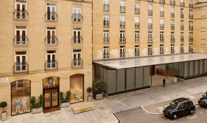 Exterior view of The Emory hotel with a stone façade, rows of balconies, and a glass entrance canopy on a city street.