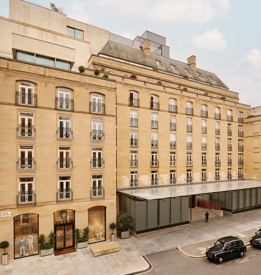 Exterior view of The Emory hotel with a stone façade, rows of balconies, and a glass entrance canopy on a city street.