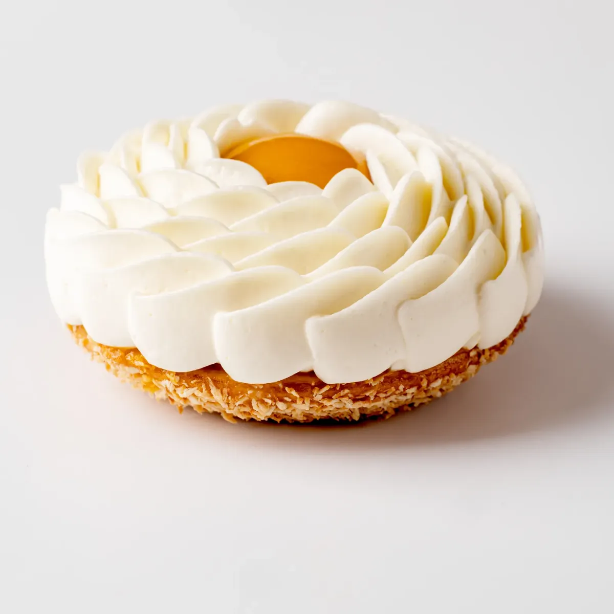 Individual pastry topped with piped cream and a glossy fruit centre, presented on a plain background.