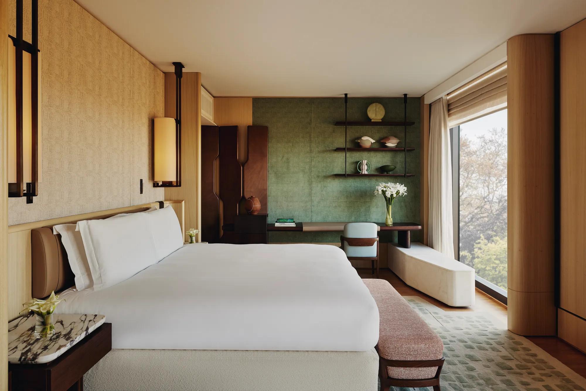 Contemporary bedroom with king bed, green feature wall, bespoke shelving, and park view through floor-to-ceiling window.