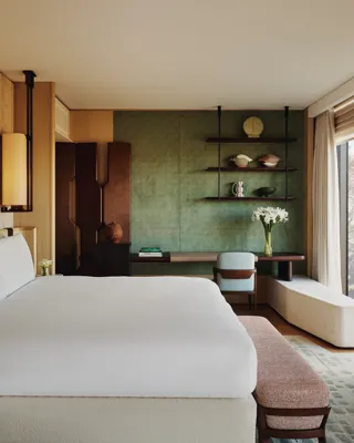 Contemporary bedroom with king bed, green feature wall, bespoke shelving, and park view through floor-to-ceiling window.