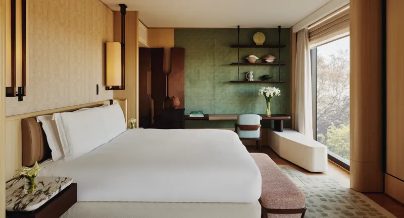 Contemporary bedroom with king bed, green feature wall, bespoke shelving, and park view through floor-to-ceiling window.