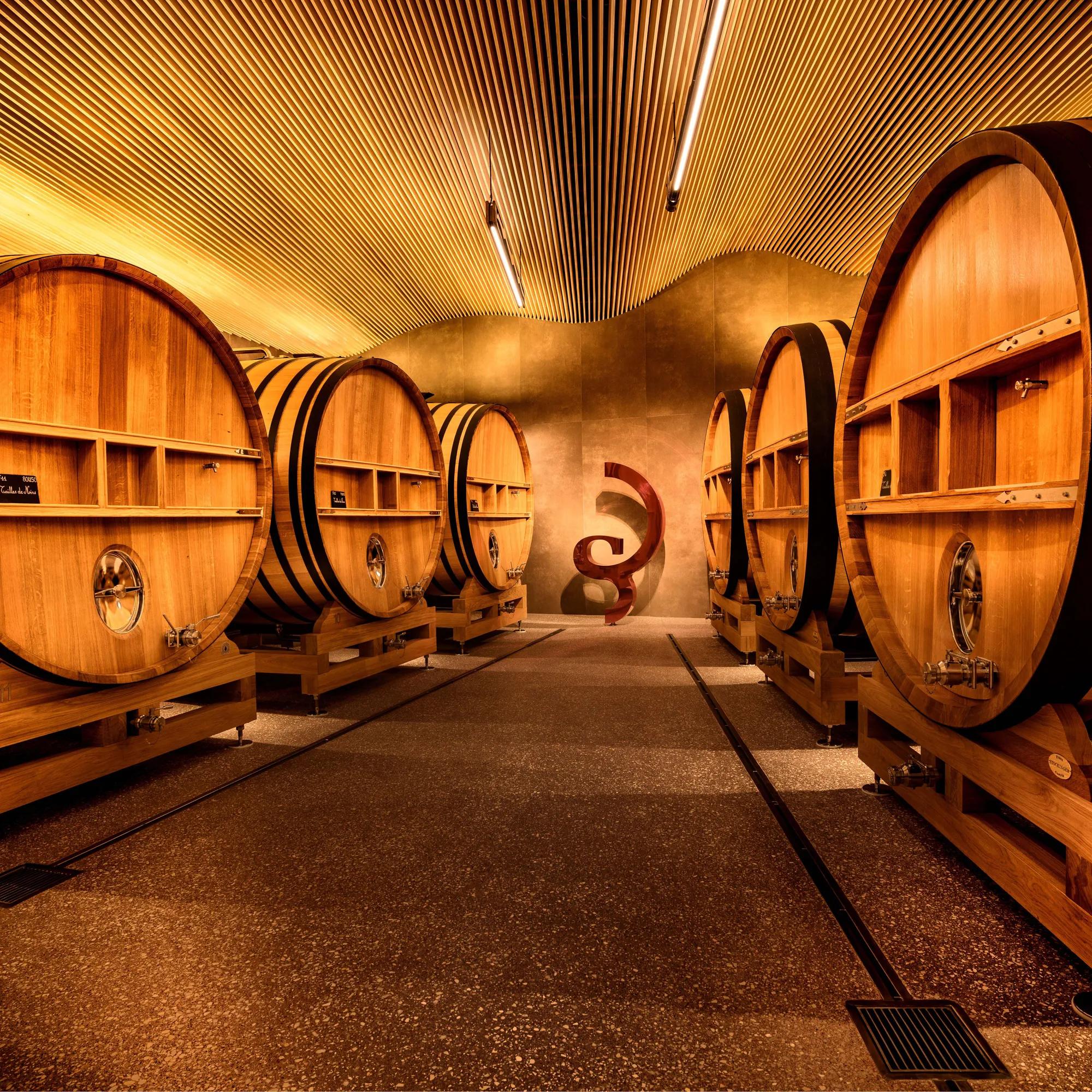A row of large wine barrels in an underground cellar