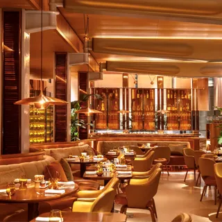 Elegant restaurant interior with warm amber lighting, curved seating, and polished tables set for dining.