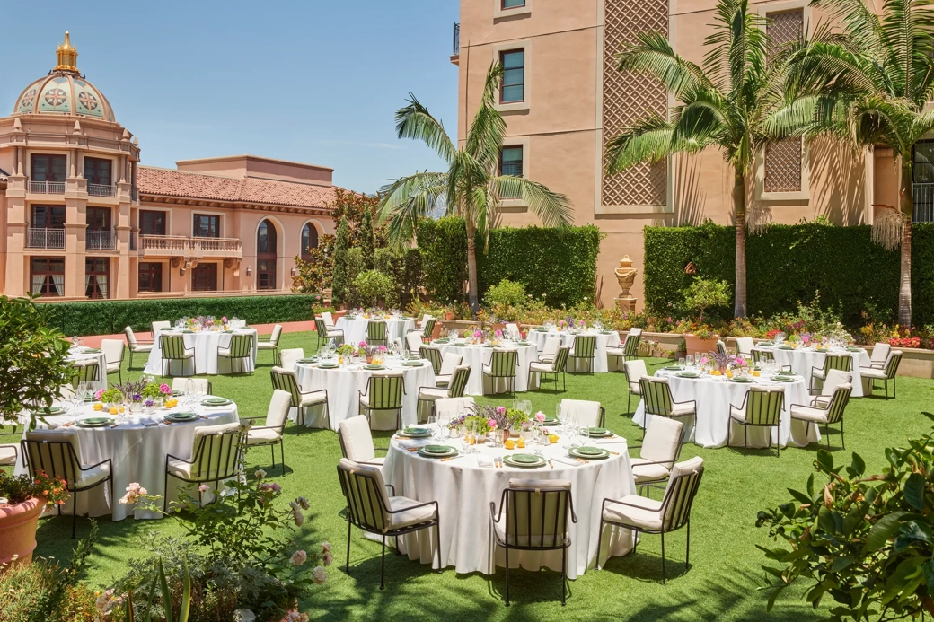Outdoor reception on the Garden Terrace with round tables, white linens, striped cushioned chairs, colorful centerpieces, palms and domed tower.