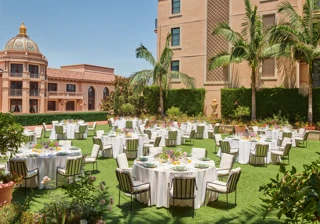 Outdoor reception on the Garden Terrace with round tables, white linens, striped cushioned chairs, colorful centerpieces, palms and domed tower.