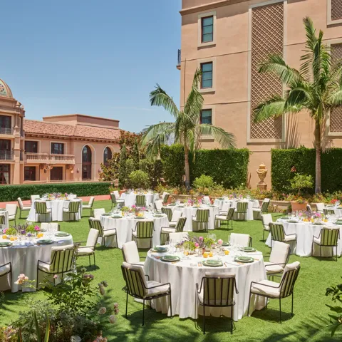 Outdoor reception on the Garden Terrace with round tables, white linens, striped cushioned chairs, colorful centerpieces, palms and domed tower.
