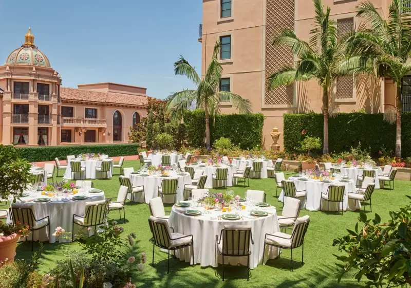 Outdoor reception on the Garden Terrace with round tables, white linens, striped cushioned chairs, colorful centerpieces, palms and domed tower.