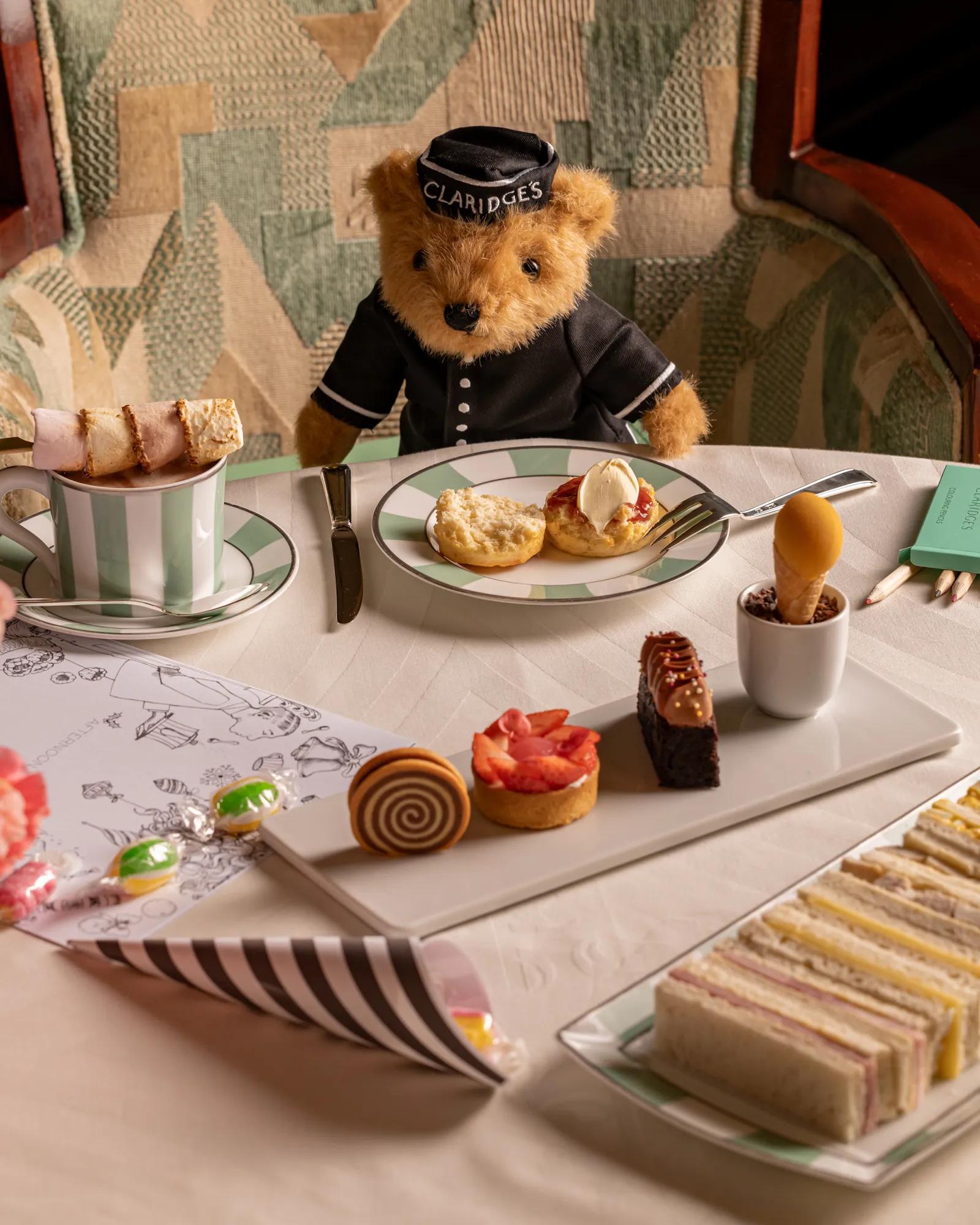 Claridge’s teddy bear at children’s afternoon tea table with scones, pastries, sandwiches and marshmallow hot chocolate.